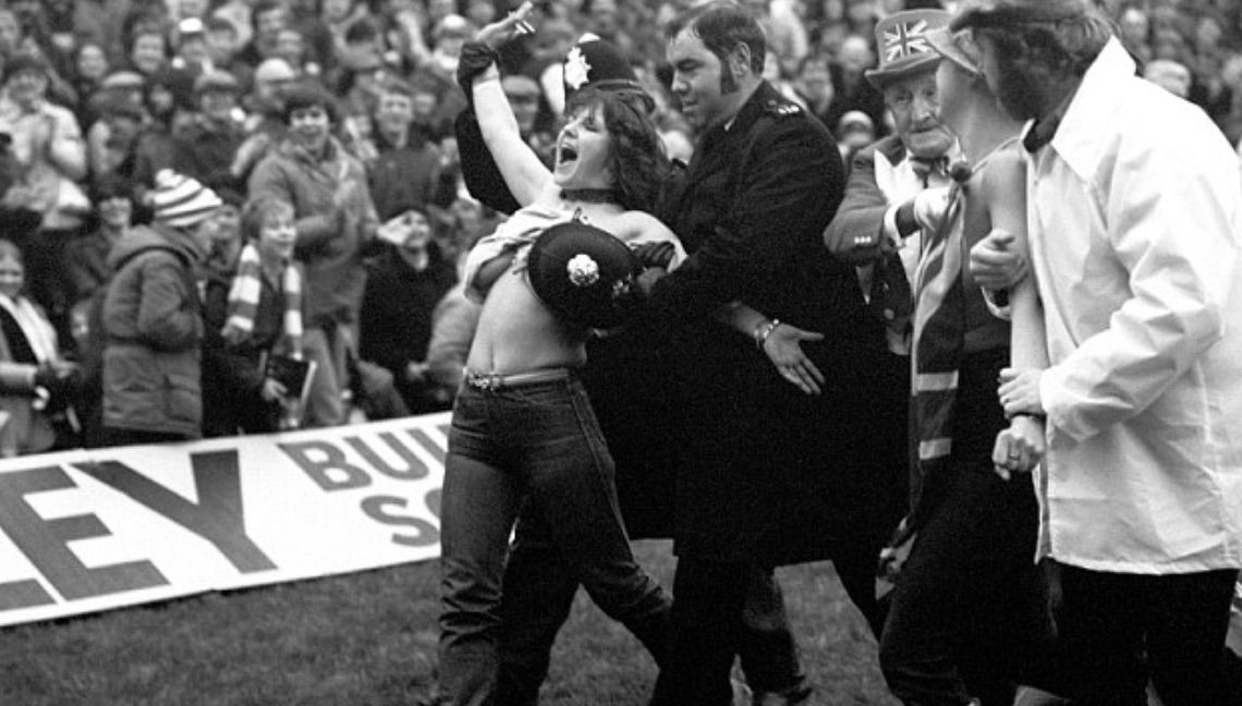 With a police helmet covering her assets, Erika Roe is escorted from the pitch. Photo: Press Association